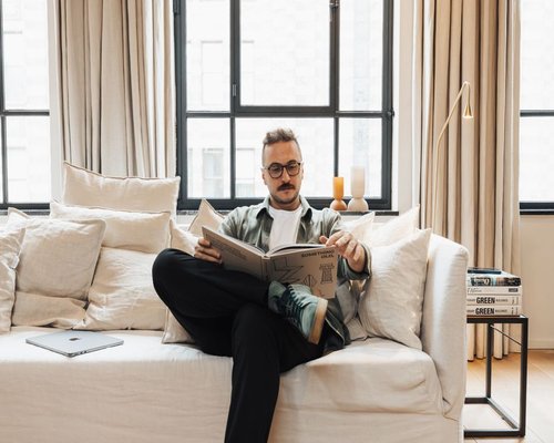 Person reading a physical book in a comfortable room setting